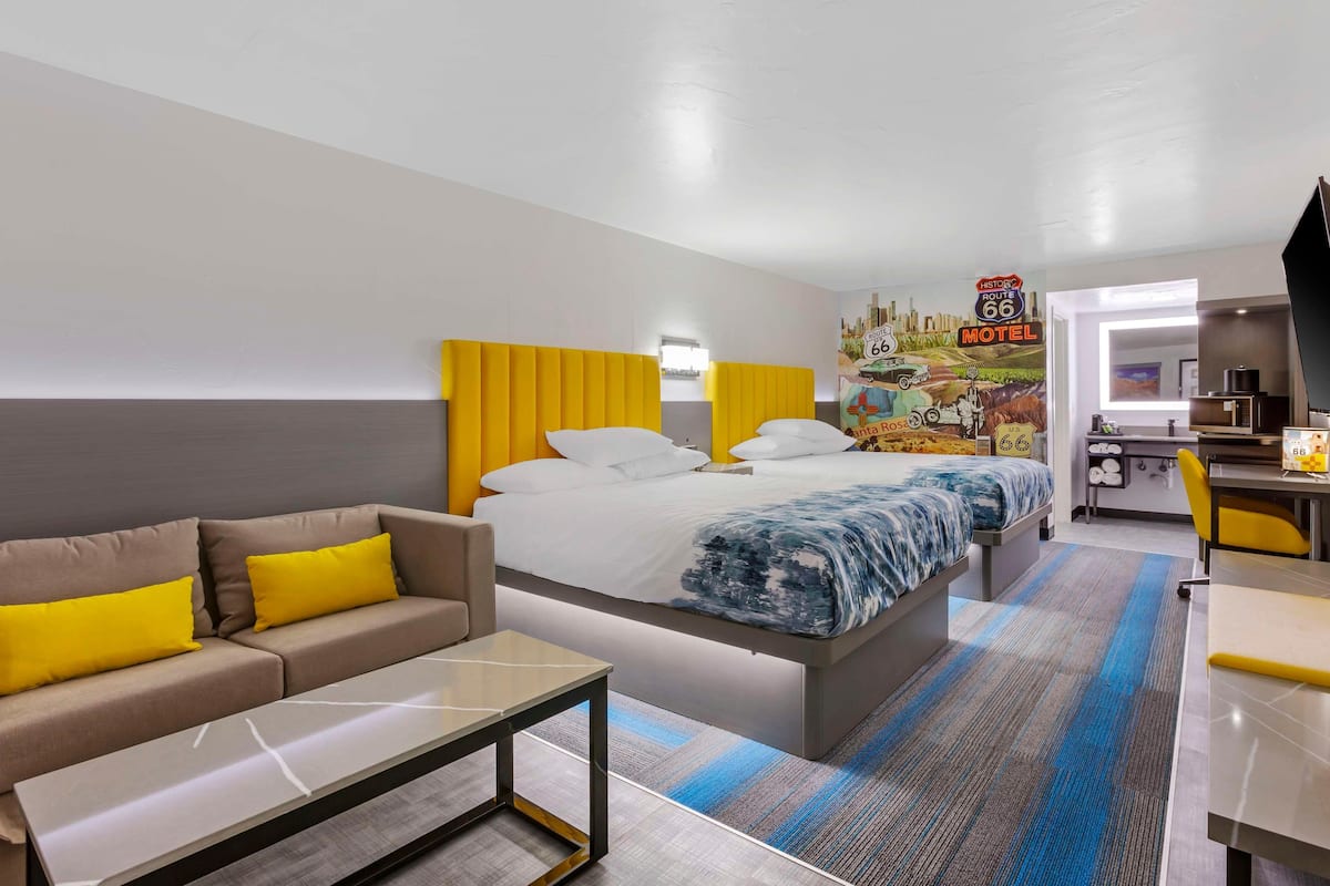 A hotel room with a bed, a sofa, a desk, and a kitchenette.