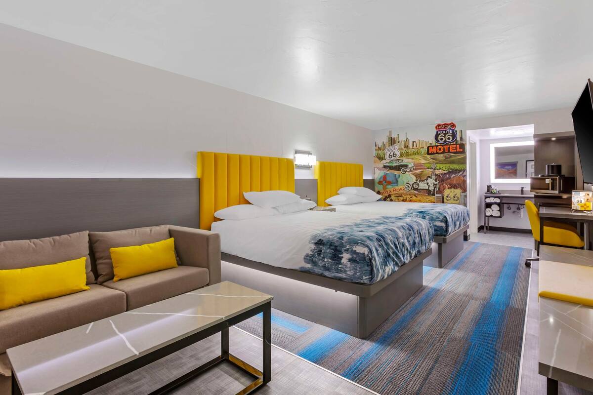 A hotel room with a bed, a sofa, a desk, and a kitchenette.
