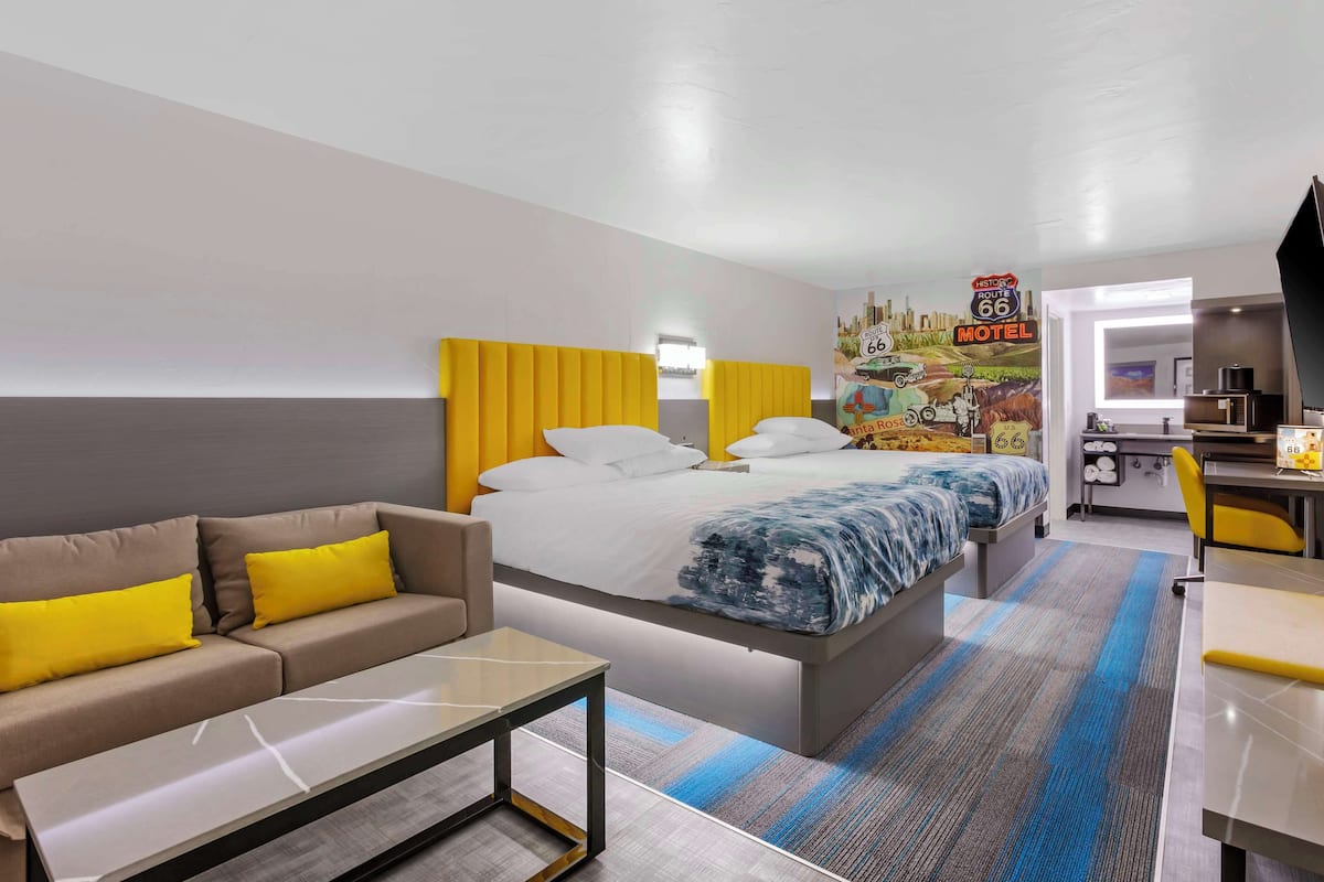 A hotel room with a bed, a sofa, a desk, and a kitchenette.