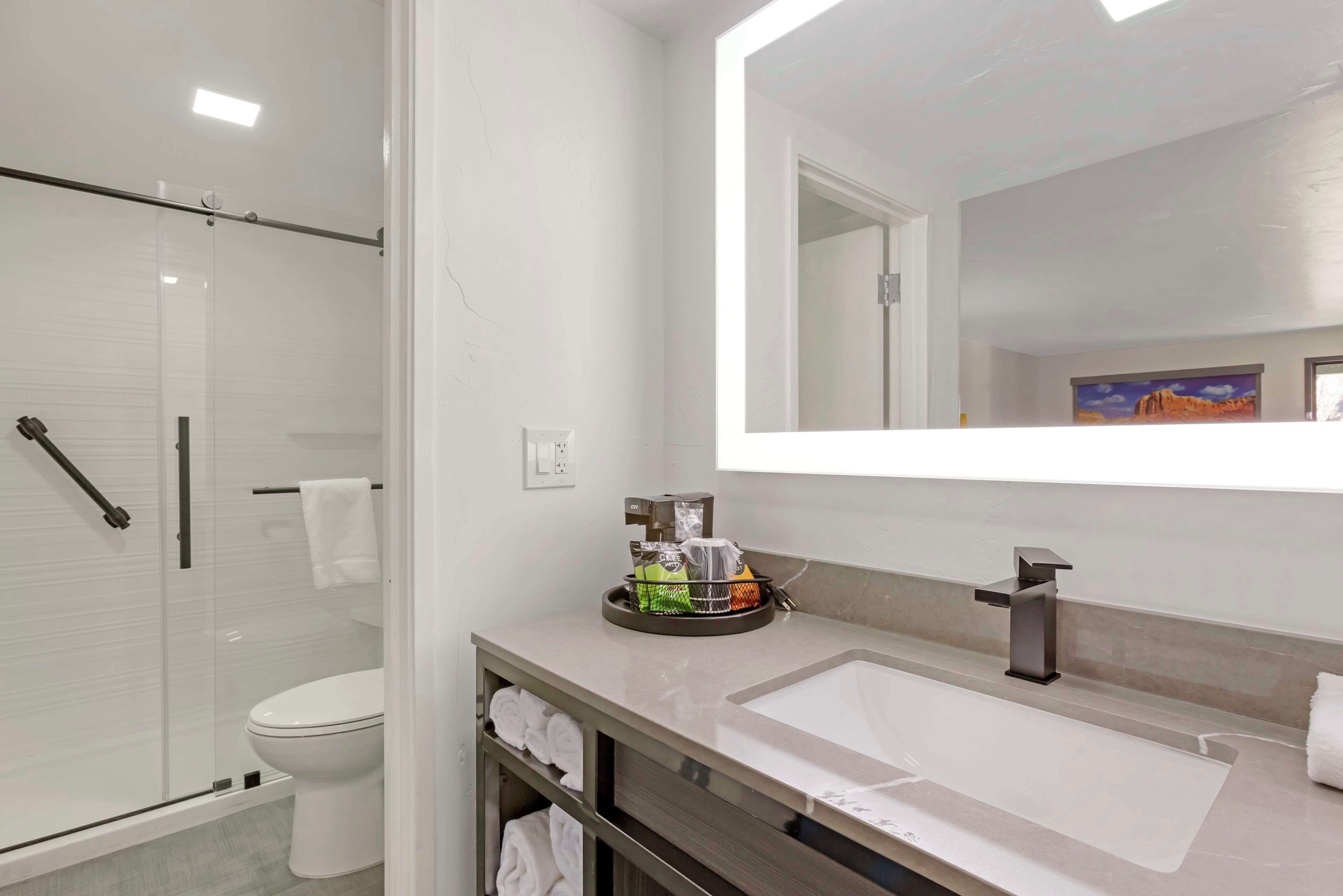 A modern bathroom with a large mirror, a sink, and a shower area.