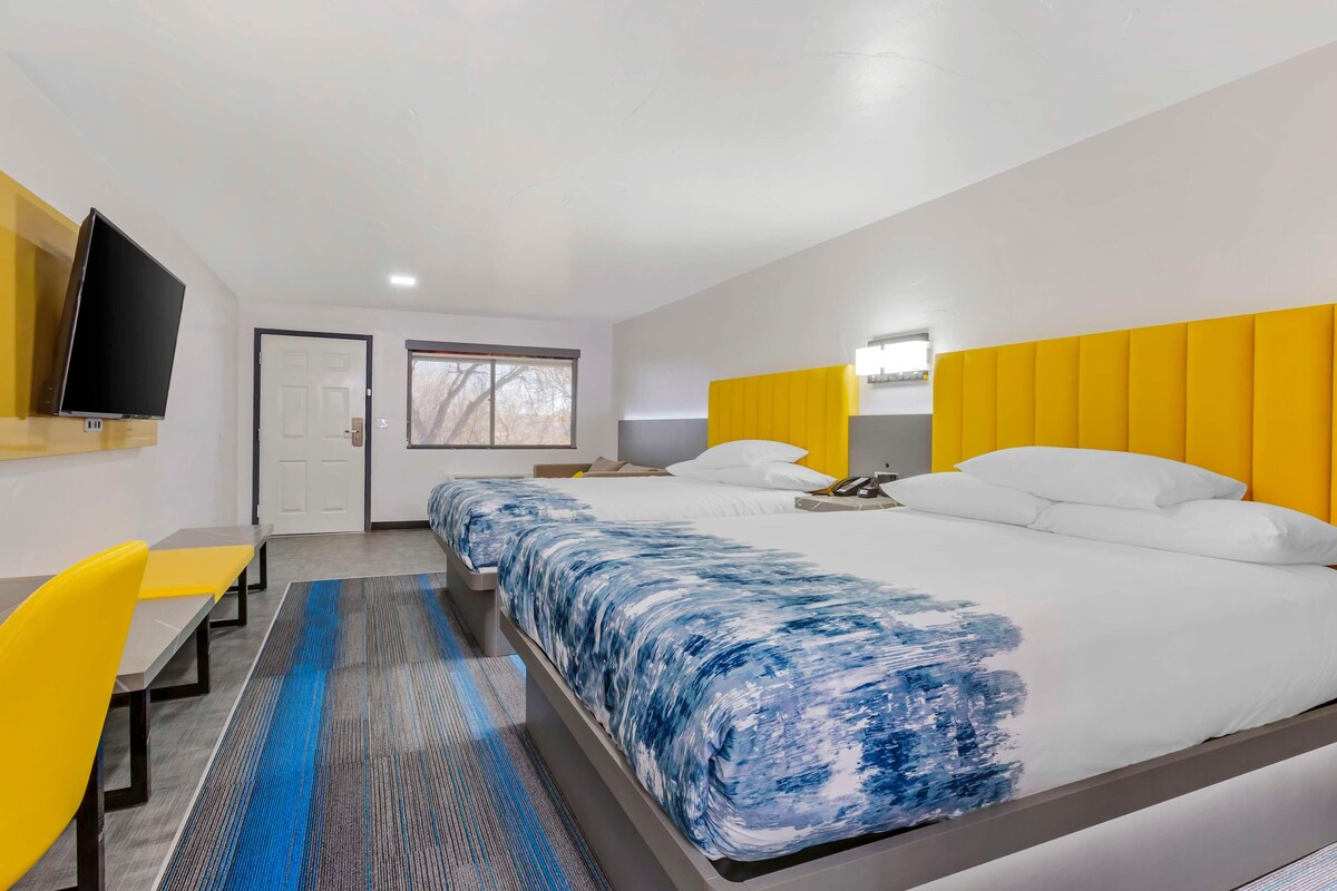 A hotel room with a bed, a TV, a desk, and a window.