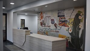 A reception desk with a light wood finish, a wall mural depicting Route 66 and other travel-related imagery, and a modern, clean interior design. - Hotel Blue 66, BW Signature Collection (Santa Rosa)