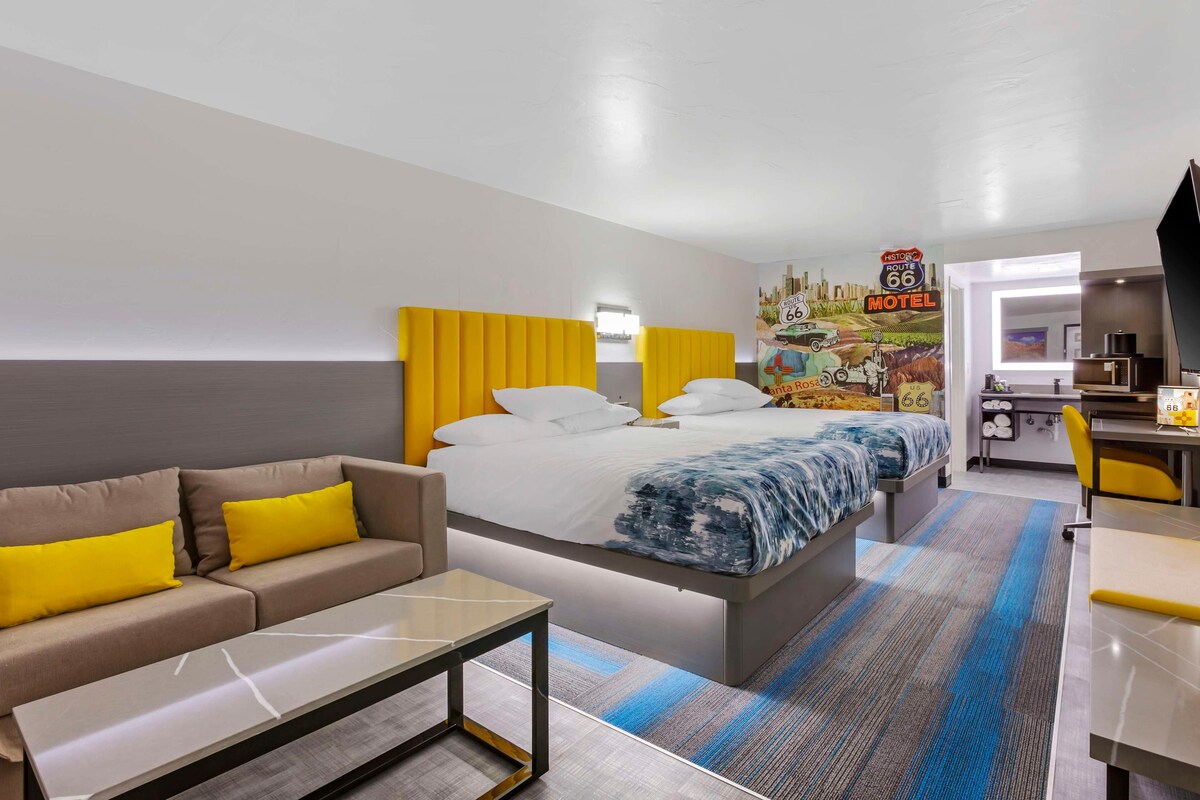 A hotel room with a bed, a sofa, a desk, and a kitchenette.
