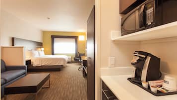 Habitación de hotel con cama, escritorio, silla, microondas y cafetera.