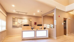 A hotel reception area with a modern design, featuring a reception desk, a mirror, and a wall-mounted sign. - Holiday Inn Express & Suites Santa Fe by IHG (Santa Fe)
