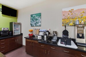 A modern kitchen with a microwave, toaster, refrigerator, and waffle maker.