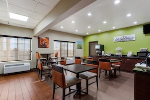 A modern dining area with tables and chairs, a kitchen area with appliances, and artwork on the walls.