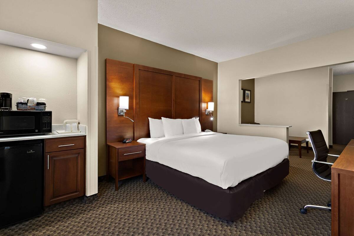 A hotel room with a large bed, a desk, a microwave, and a coffee maker.
