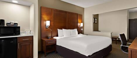 A hotel room with a large bed, a desk, a microwave, and a coffee maker.