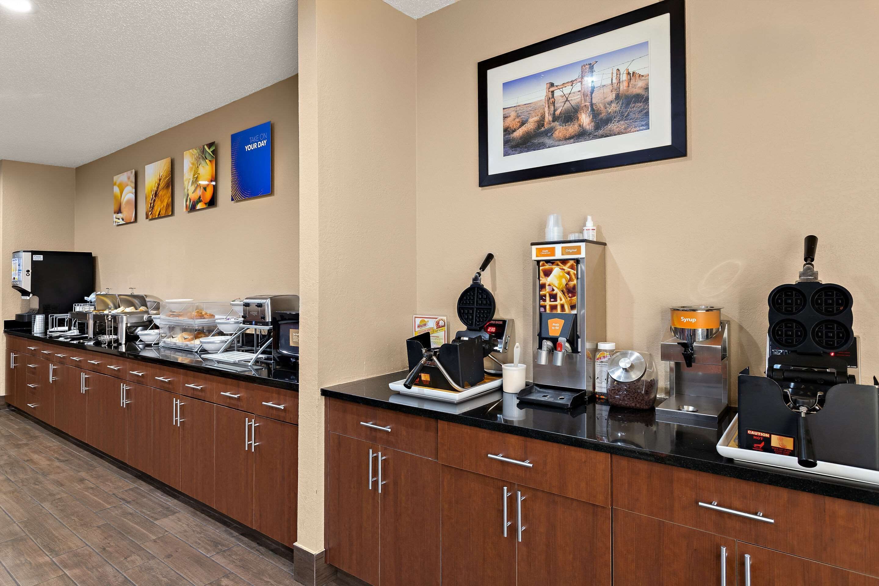 A hotel breakfast area with a long counter, coffee machines, and a waffle maker.