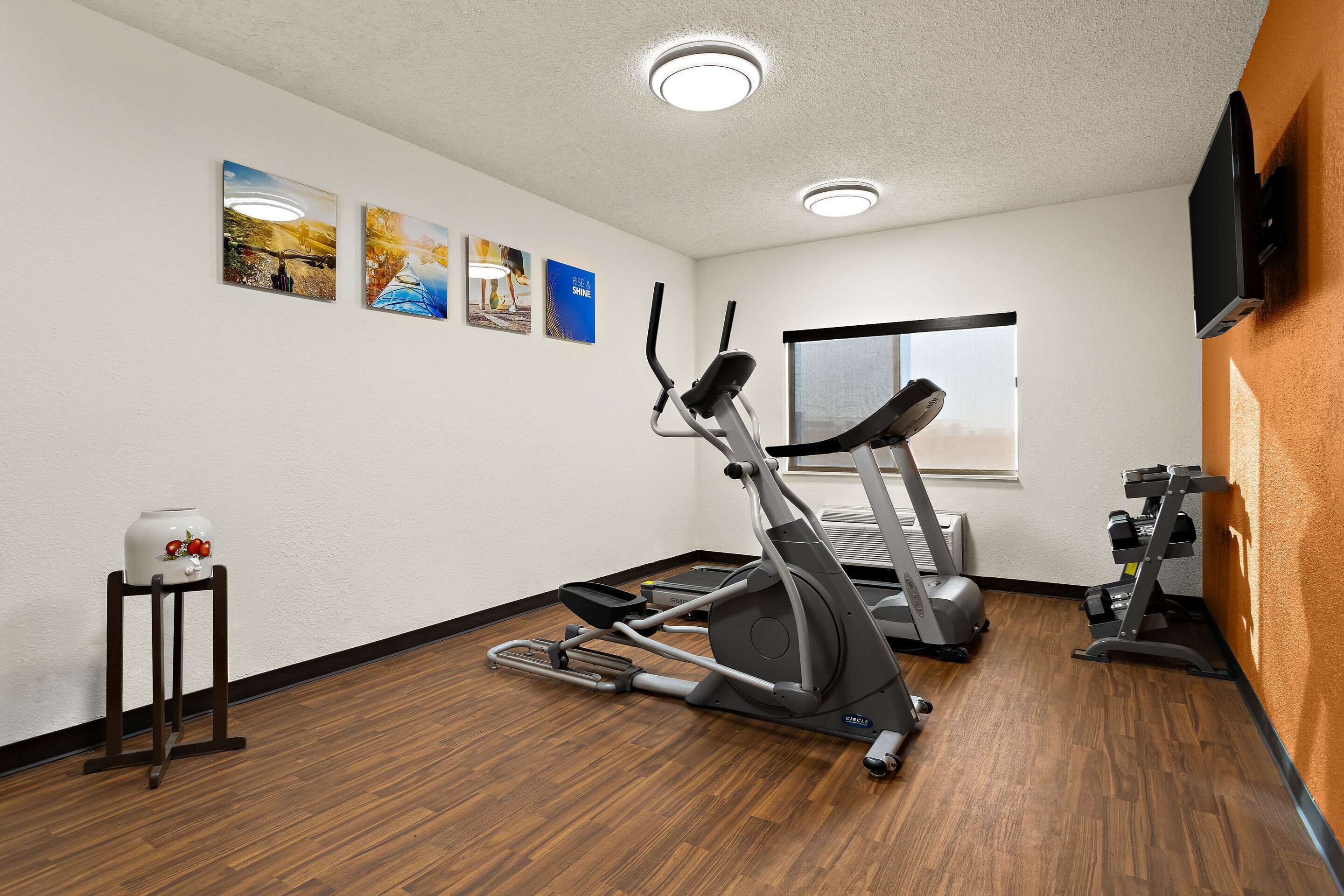 A gym with exercise equipment, a standing fan, and wall art.