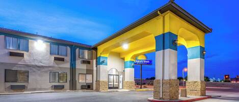 A Days Inn hotel with a covered entrance, stone pillars, and a clear sky.
