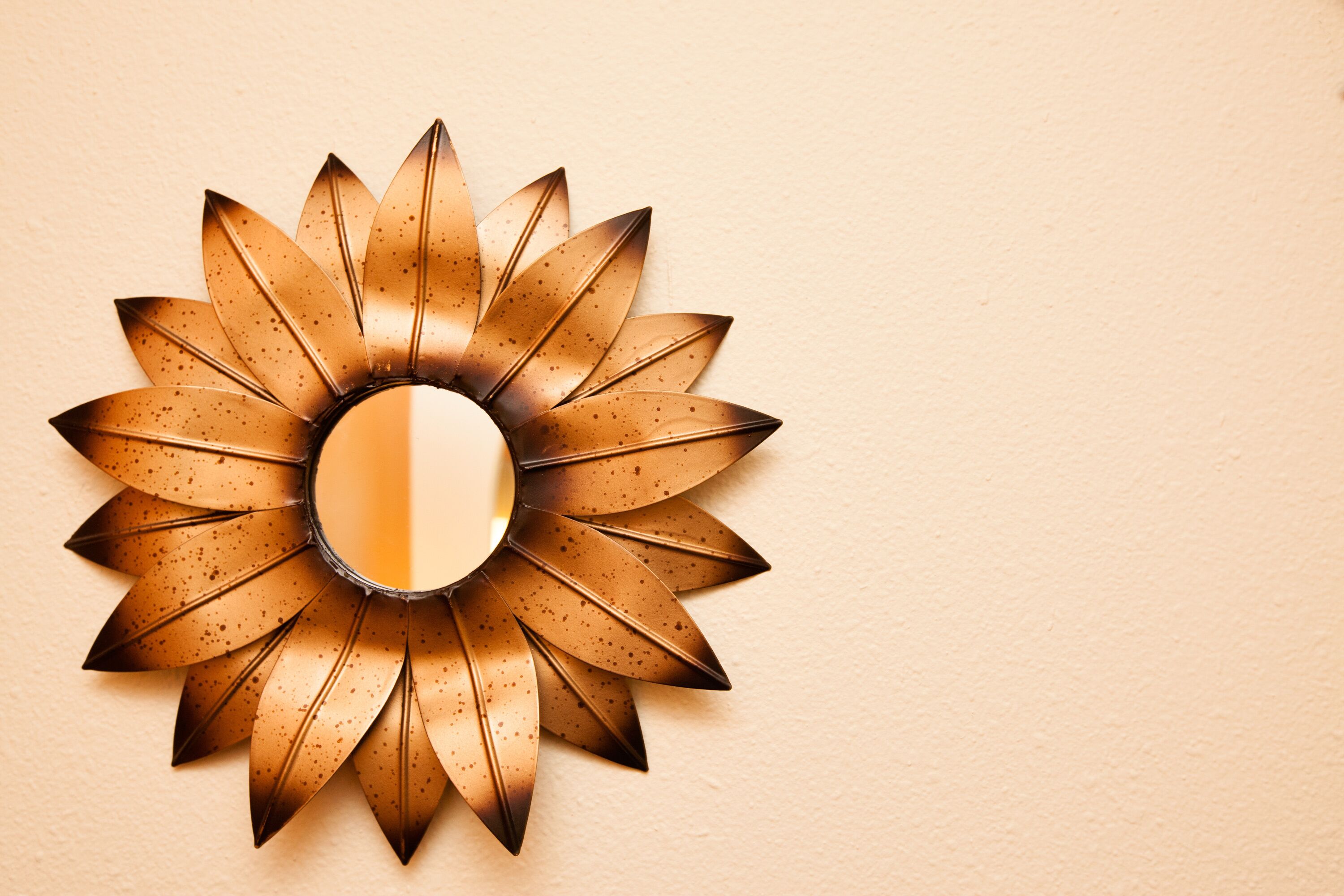 A wall-mounted sunburst mirror with a reflective center.
