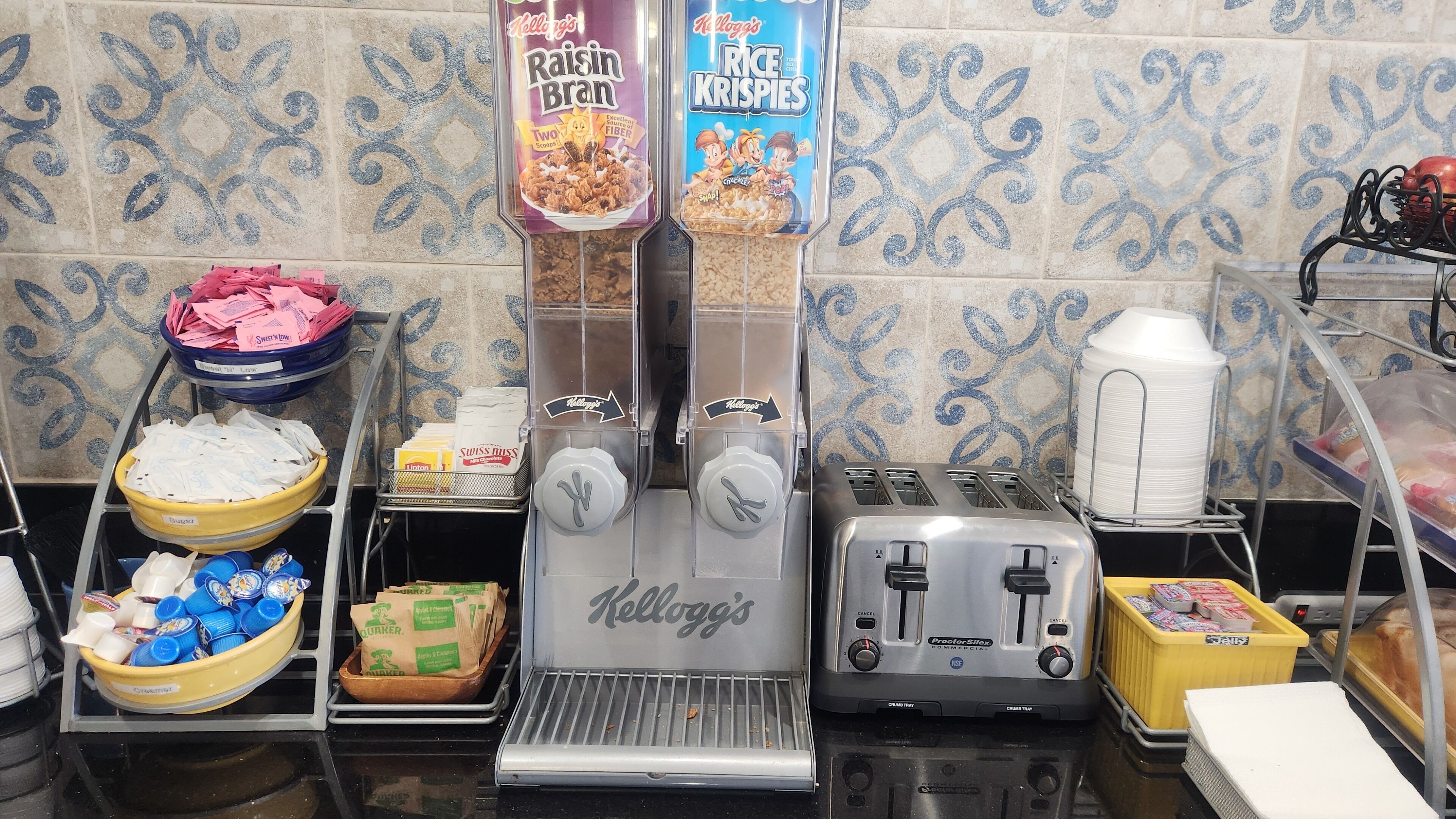Een ontbijtbuffet met cornflakes, een koffieapparaat en een broodrooster.