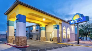 A Days Inn by Wyndham with a yellow and blue facade, stone pillars, and a covered entrance.