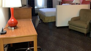 A hotel room with a desk, a chair, a bed, a small sofa, and a trash bin. - Ramada by Wyndham Santa Fe (Santa Fe)