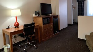 A hotel room with a desk, chair, television, microwave, and refrigerator. - Ramada by Wyndham Santa Fe (Santa Fe)