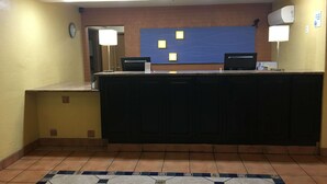 A reception area with a desk, two computers, a clock, and a blue wall with light fixtures. - Ramada by Wyndham Santa Fe (Santa Fe)
