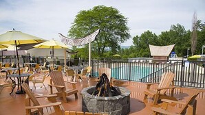 A poolside area with wooden chairs, tables, and umbrellas. - Tiki Resort (Lake George)
