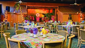 A restaurant with round tables set with colorful tablecloths, chairs, and table settings.