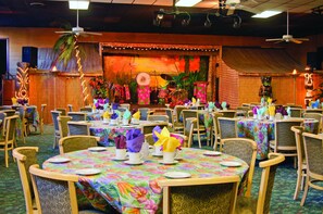 A restaurant with round tables set with colorful tablecloths, chairs, and table settings.