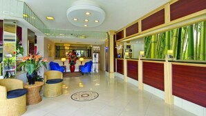A spacious lobby with a reception desk, seating area, and a staircase.
