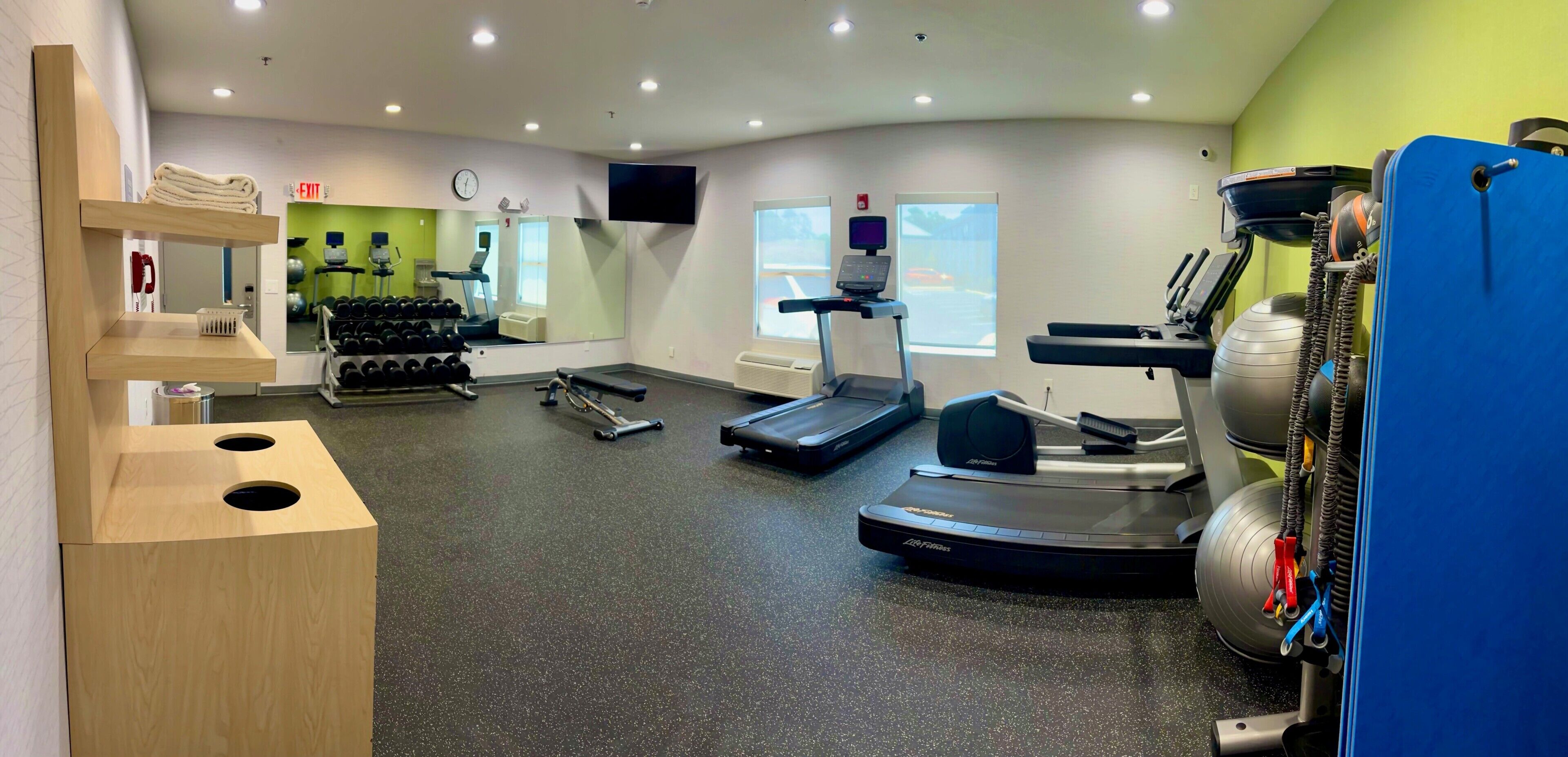 Ein Fitnessstudio mit Laufbändern, Kurzhanteln und Trainingsgeräten.