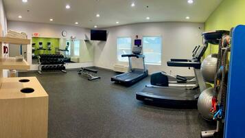 Ein Fitnessstudio mit Laufbändern, Kurzhanteln und Trainingsgeräten.