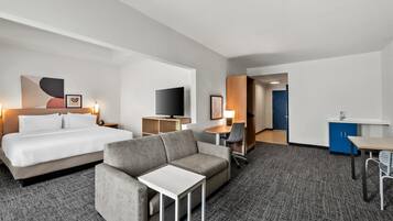 Une chambre d’hôtel comprenant un lit, un canapé, une télévision, un bureau et une kitchenette.