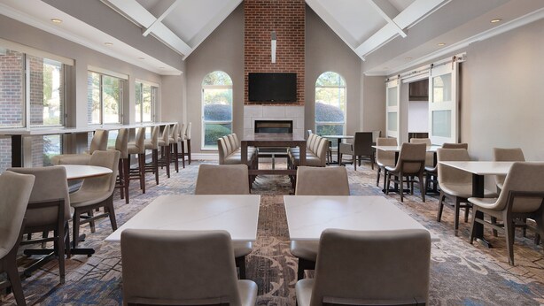 A conference room with a brick fireplace, large windows, and a carpeted floor. - Residence Inn by Marriott Southern Pines/Pinehurst NC (Southern Pines)
