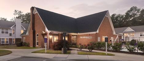 A brick building with a distinctive triangular roof, labeled "Residence Inn by Marriott," featuring a well-maintained lawn and a parking lot.