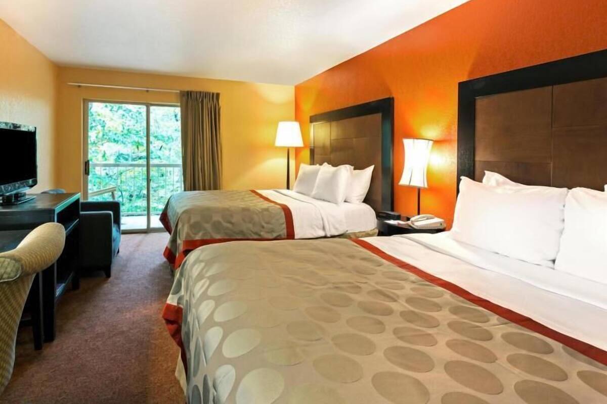Une chambre d’hôtel avec deux lits, un bureau et une télévision.