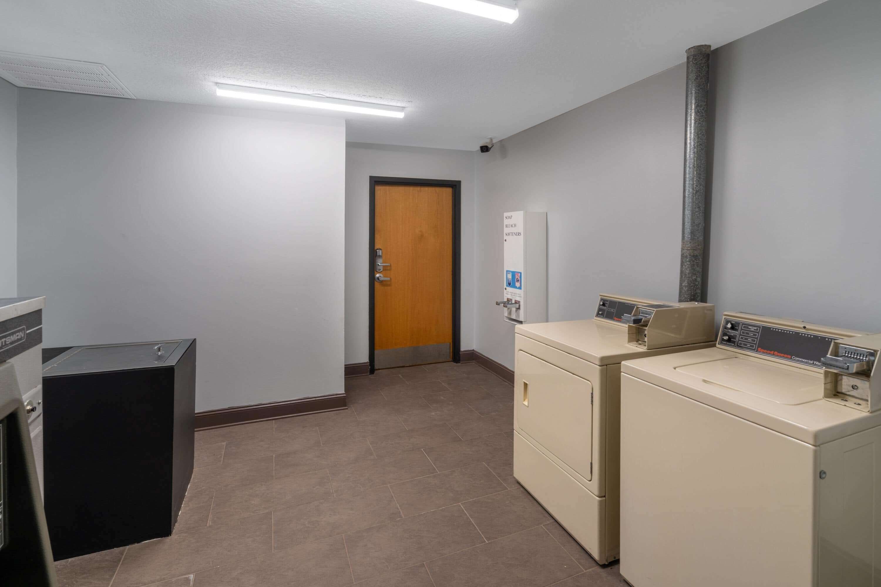 A laundry room with a washing machine, dryer, and a small black cabinet.