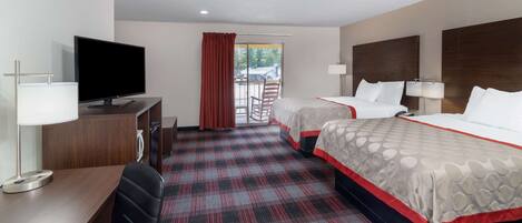 A hotel room with two beds, a desk with a TV, a chair, and a view of the outdoors.