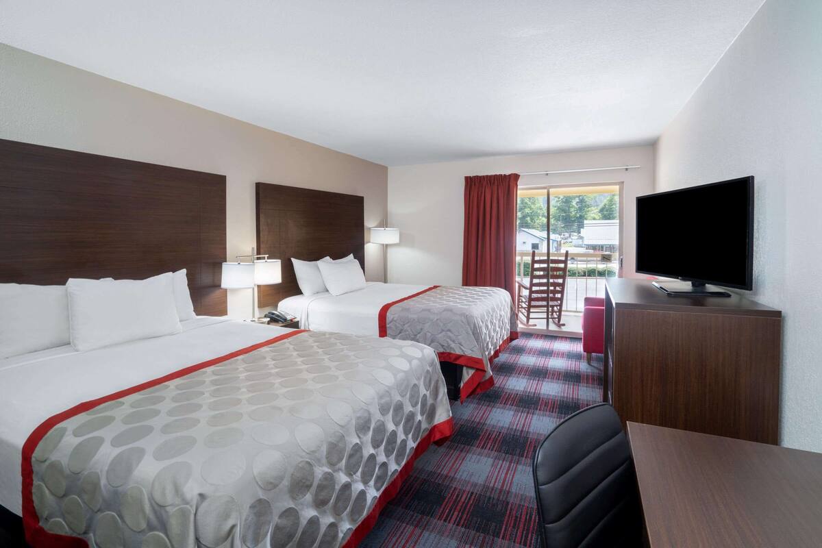 Une chambre d’hôtel avec deux lits, une télévision, un bureau et une vue sur l’extérieur.