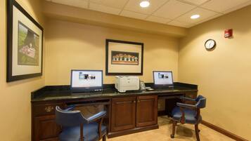 A reception area with two computers, a printer, and two blue chairs.