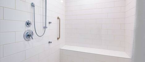 A modern shower area with white tiles, a handheld showerhead, and a handheld shower attachment.