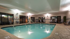 Une piscine intérieure dotée de chaises longues et d’un panneau indiquant la profondeur de la piscine pour les plongeons.