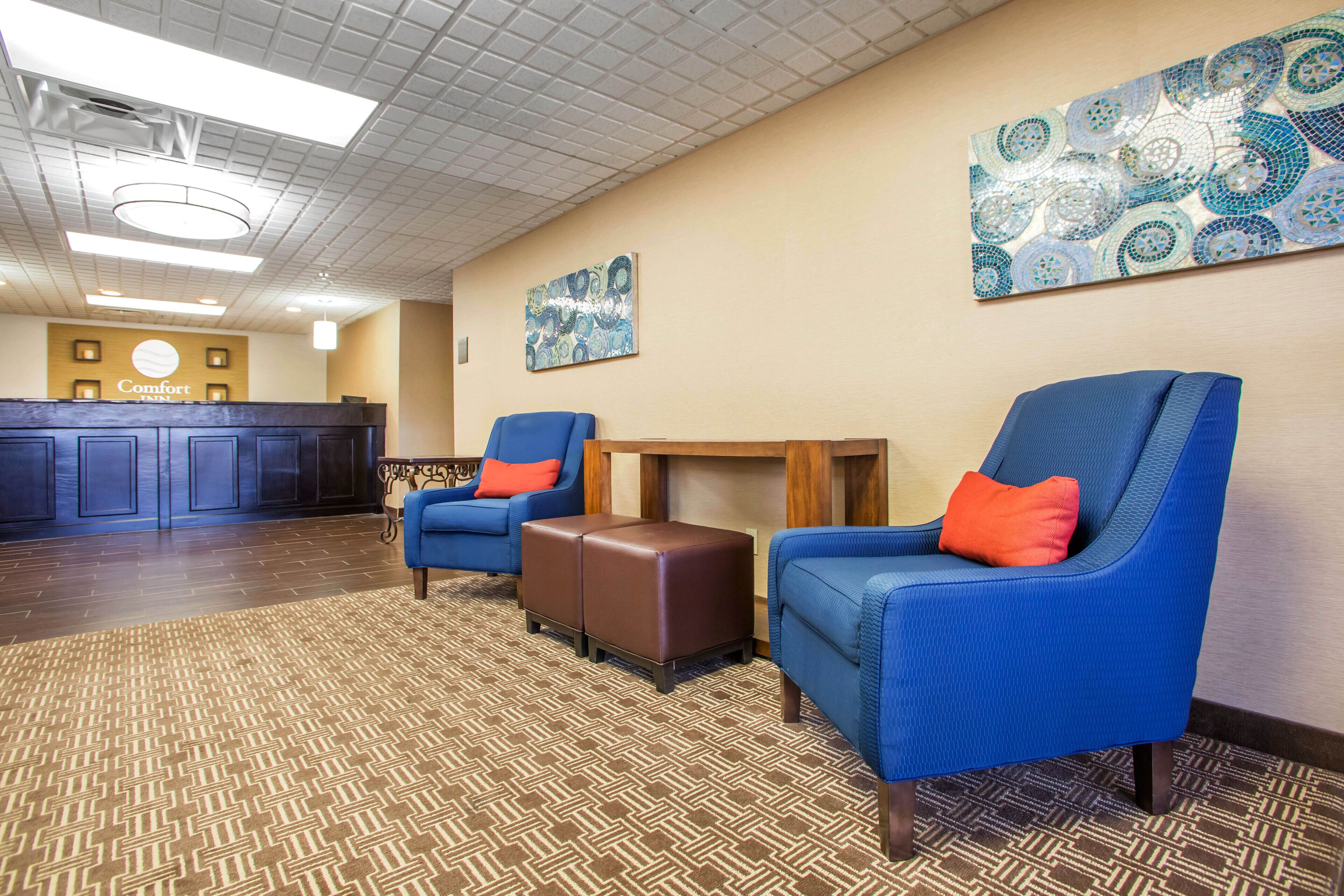 Un vestíbulo de hotel con sillones azules, una recepción y alfombra estampada.