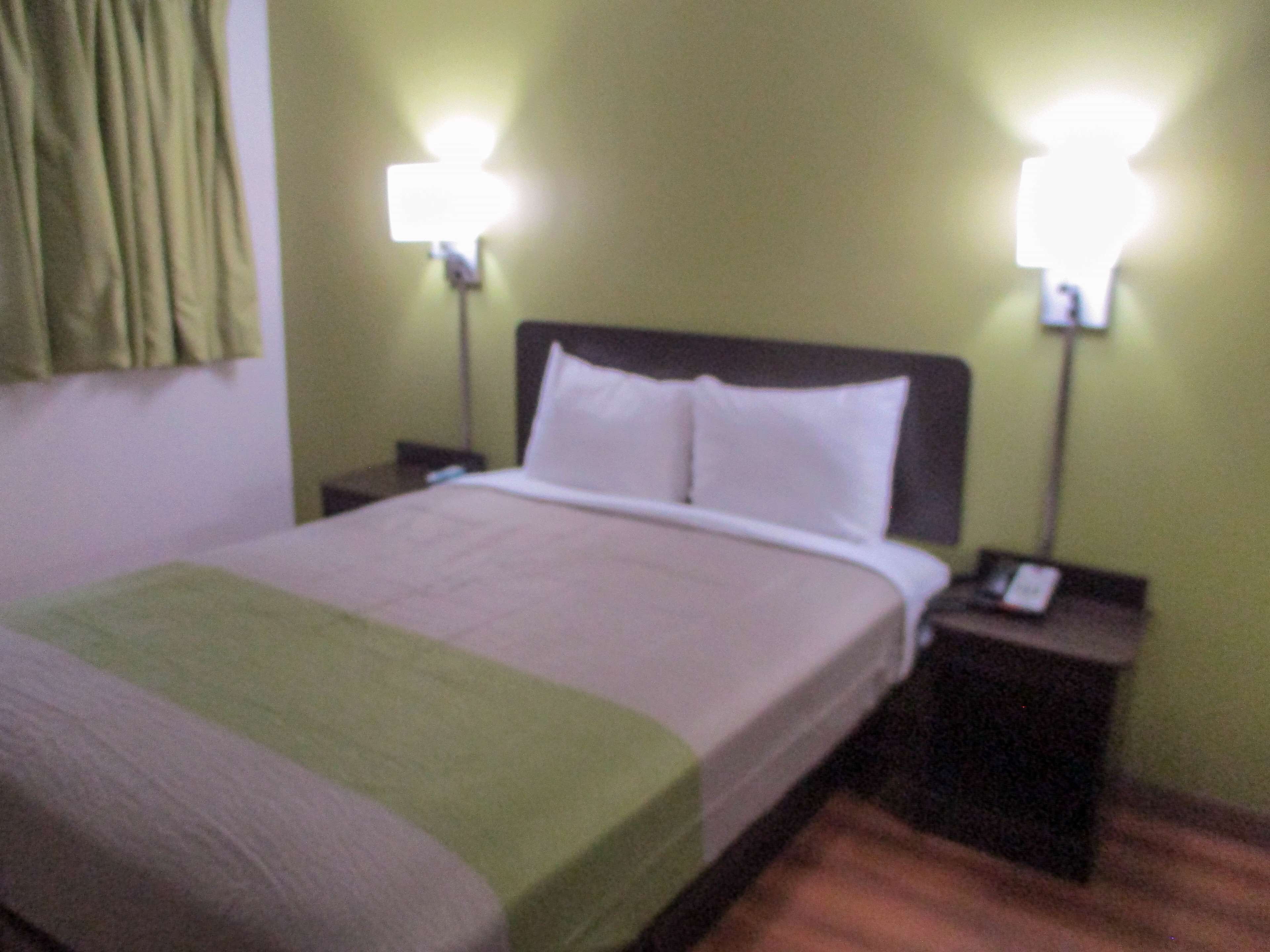 A hotel room with a bed, two bedside tables, and two wall-mounted lamps.