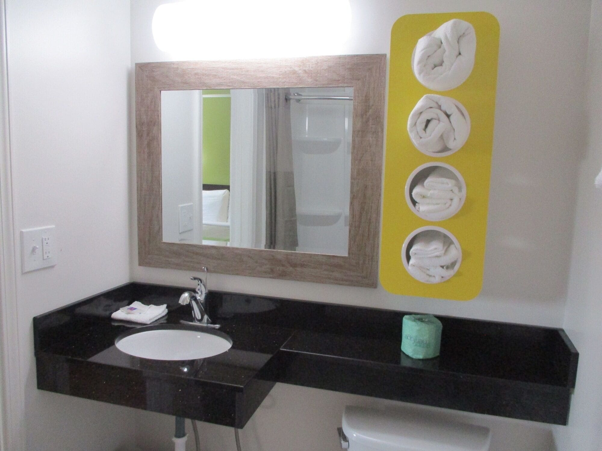 Une salle de bain avec un lavabo au comptoir noir, un miroir et un porte-serviettes avec quatre serviettes.