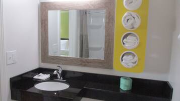 Une salle de bain avec un lavabo au comptoir noir, un miroir et un porte-serviettes avec quatre serviettes.