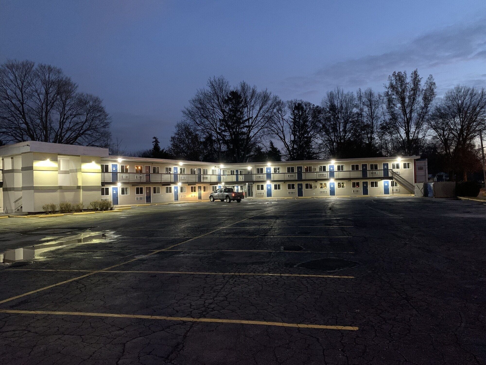 A motel with multiple floors, a parking lot, and a truck parked in the lot.