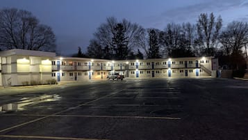 A motel with multiple floors, a parking lot, and a truck parked in the lot.