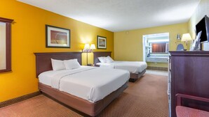 Habitación de hotel con dos camas, un escritorio, una silla, un televisor y un baño visible a través de una puerta abierta.