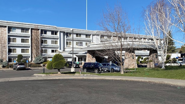 Un edificio de varios pisos con un estacionamiento al frente.