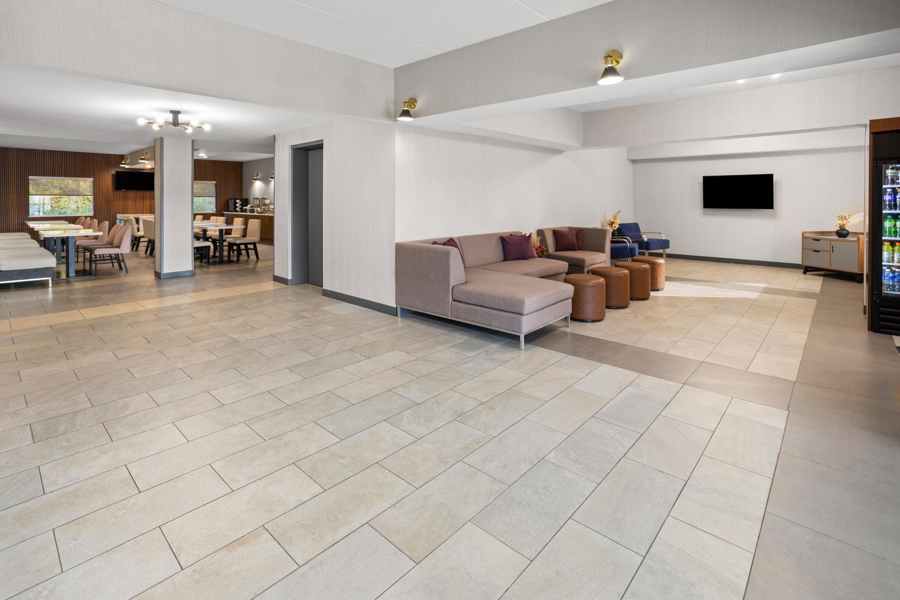 A spacious lobby with a seating area, a television, and a vending machine.