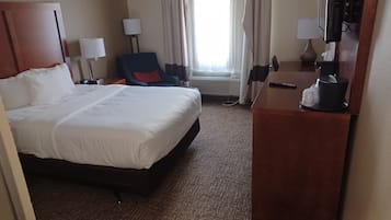 Une chambre d’hôtel avec un grand lit, un bureau avec une lampe, une chaise et un téléviseur.