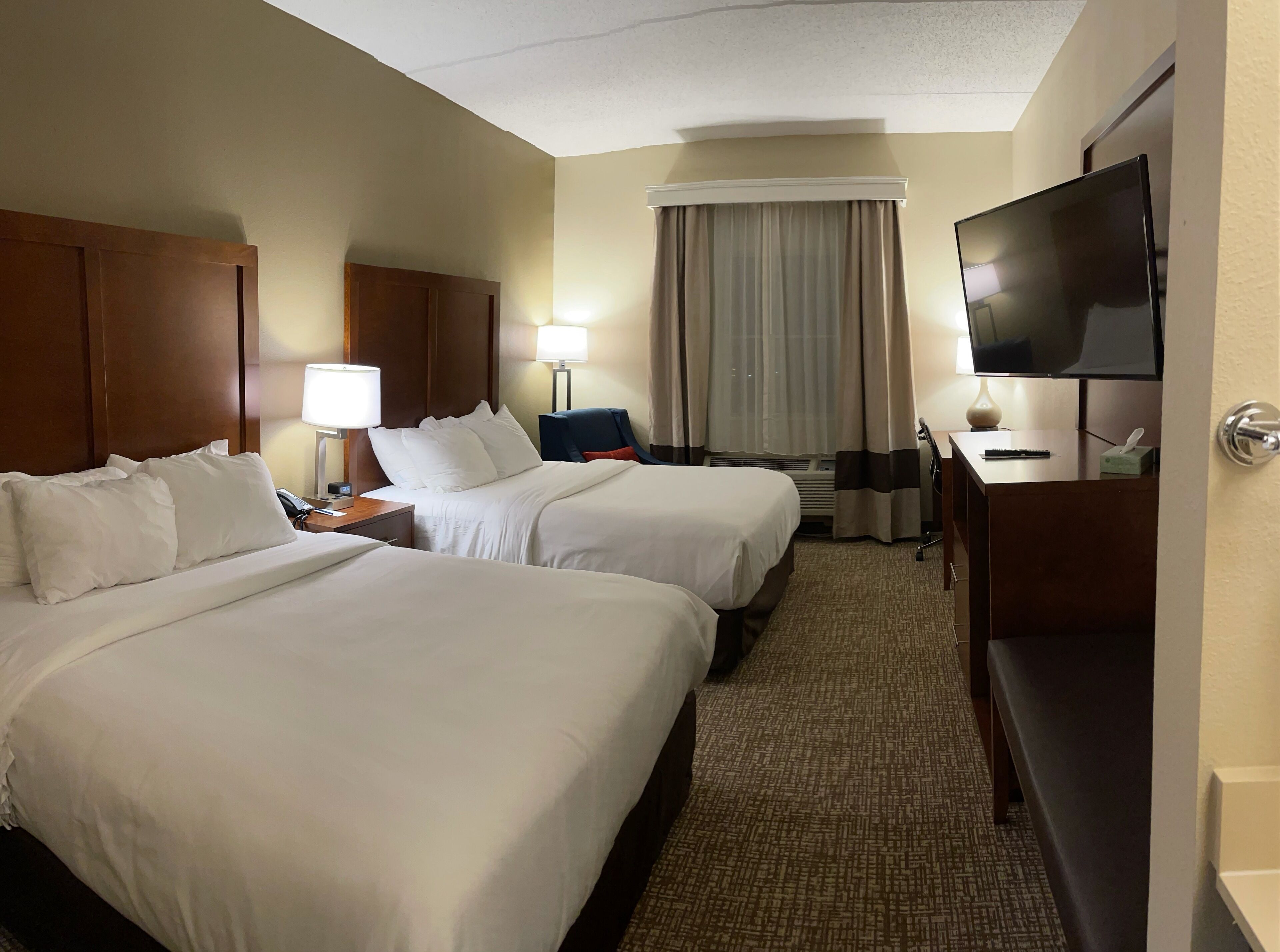A hotel room with two beds, a TV, a desk, and a chair.