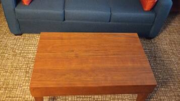 A blue sofa with two red cushions and a wooden coffee table in front of it.